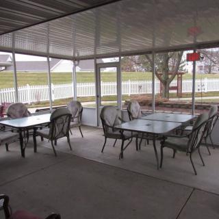 A covered outdoor patio with tables and chairs arranged for seating.