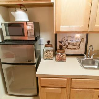 A compact kitchen setup featuring a microwave, mini fridge, and countertop with decorative containers.