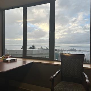 A serene office space featuring a large window with a view of the sky and water.