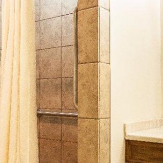 A tiled shower with a curtain in a bathroom setting.
