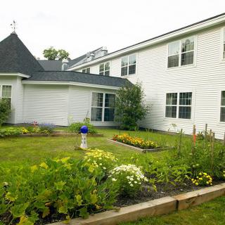 A white residential building with a beautifully maintained garden in the foreground.