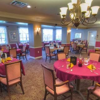 A cozy dining area with elegantly set tables and a chandelier overhead.