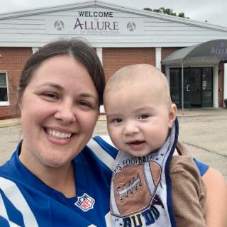 A joyful moment captured between a mother and her baby outside a welcoming building.