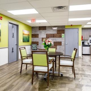 A modern dining area with a table and chairs, featuring colorful decor and wood flooring.