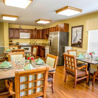 A cozy dining area with a well-set table, adjacent to a modern kitchen featuring wooden cabinets and stainless steel appliances.