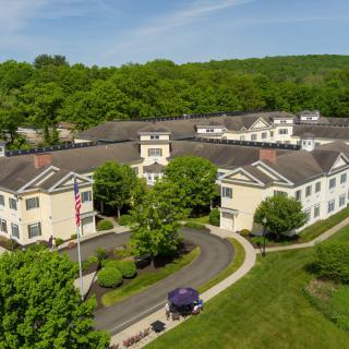 Aerial view of a large building surrounded by greenery and roads.