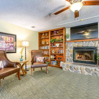 A cozy living room with a stone fireplace, comfortable armchairs, and a well-organized bookshelf.