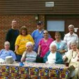 A group of people gathered around a table outdoors, enjoying a casual get-together.