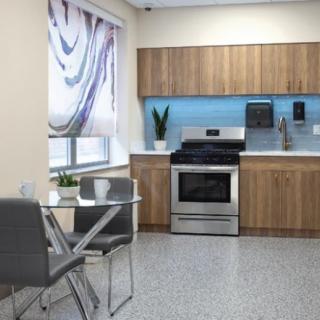 A modern kitchen with stainless steel appliances, wooden cabinets, and a small dining area.