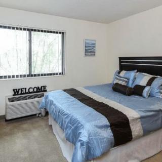 A modern bedroom with a neatly made bed and large window.
