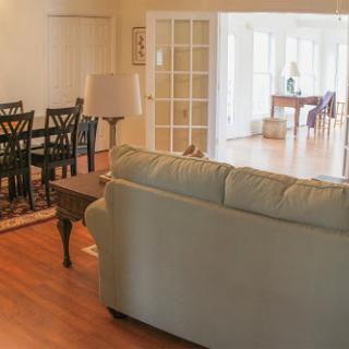 A cozy living room featuring a comfortable sofa, a dining area with chairs, and plenty of natural light.