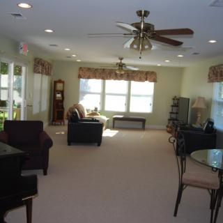 A spacious living room with several chairs, a sofa, a coffee table, and large windows letting in natural light.
