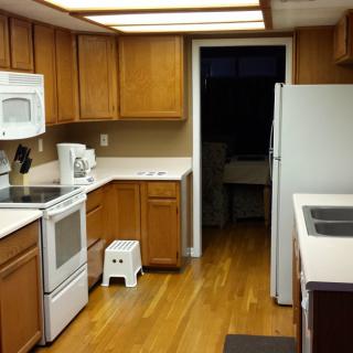 A clean kitchen with wooden cabinets, white countertops, and modern appliances.