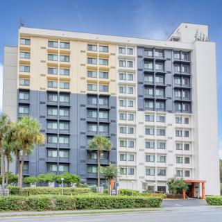 A multi-story hotel building with a modern facade and palm trees lining the front.