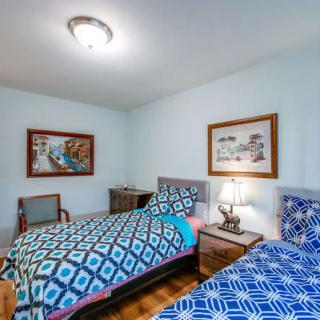 A cozy bedroom featuring two twin beds with blue patterned bedspreads, complemented by a lamp and framed artwork on the walls.