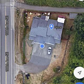 Aerial view of a house with a driveway and surrounding trees.