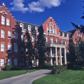 A historic red brick building with classical architecture on a sunny day.