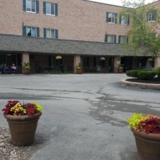 A brick building with flower pots in the foreground and a parking lot.