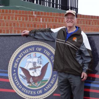 A person posing next to a military seal outdoors.