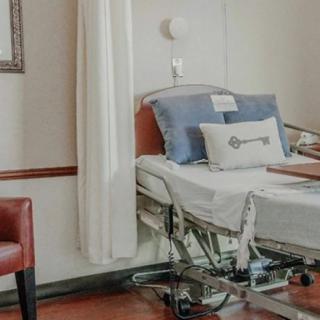 A hospital room with a neatly made bed and medical equipment.