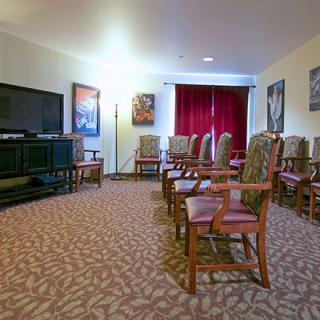 A conference room with neatly arranged chairs facing a large television screen.