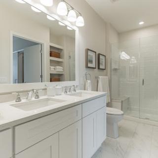 A modern bathroom featuring a double vanity with sinks, a large shower, and neutral-toned decor.