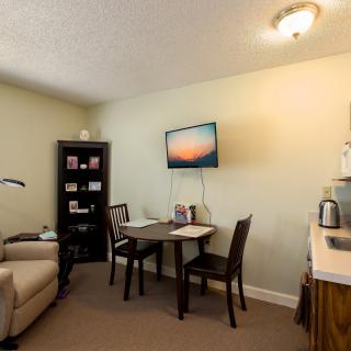 A cozy office space with a table, chairs, and a wall-mounted television.