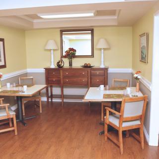 A cozy dining area with wooden tables and chairs, a decorative cabinet, and lamps on either side.