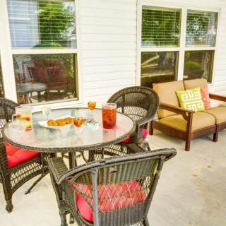 An inviting patio area with a round table, chairs, and a cozy sofa adorned with cushions.