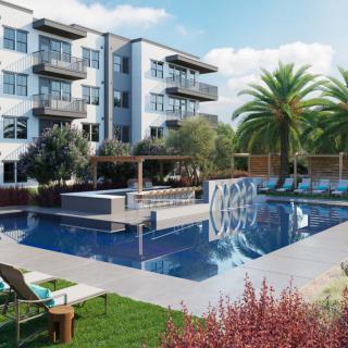 A modern residential complex with a luxurious outdoor swimming pool surrounded by lush landscaping.