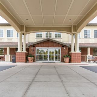 Covered entrance of a building with columns and glass doors.