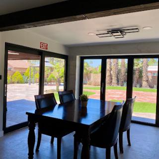 A modern dining room featuring a wooden table and chairs with large windows offering an outdoor view.