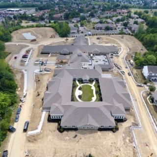 Aerial view of a construction site featuring a large building and surrounding land development in a suburban area.