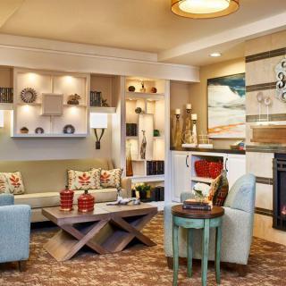 A modern living room with stylish furniture and decorative elements, featuring a cozy seating area and elegant shelving.