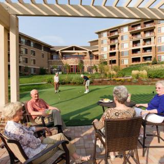 Seniors enjoy a sunny day outdoors, socializing and playing lawn games in a retirement community.