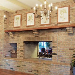 A cozy living room with a brick fireplace, chandelier, and framed art above the mantel.