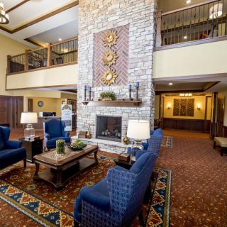 A luxurious hotel lobby featuring a stone fireplace, blue upholstered chairs, and elegant decor.