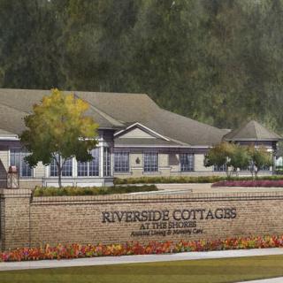 A view of the Riverside Cottages with a brick sign and landscaped surroundings.