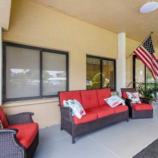 A cozy patio with red-cushioned wicker furniture and an American flag.