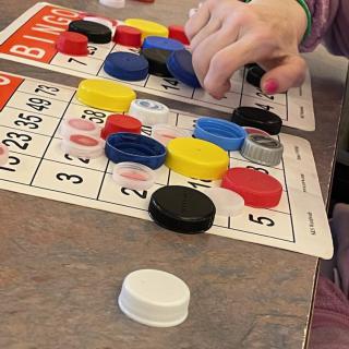 A child plays bingo using colorful bottle caps as markers.