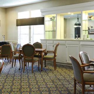 A well-lit dining area featuring several tables and chairs with decorative carpeting.