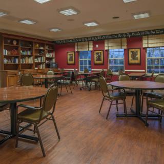 A cozy library reading room with tables and chairs surrounded by bookshelves.