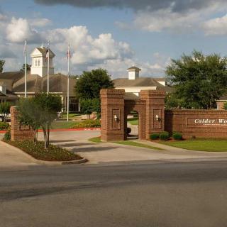 Entrance with brick gates and a cloudy sky in the background.