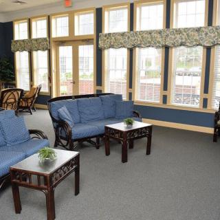 A cozy living room with blue sofas, wooden coffee tables, and large windows.