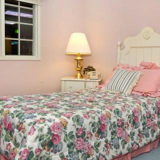 A cozy bedroom with floral bedding and pink walls.