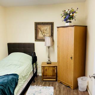 A cozy bedroom with a single bed, nightstand, lamp, and wardrobe.