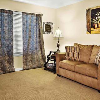 A cozy living room featuring a brown sofa, patterned curtains, and elegant decor.