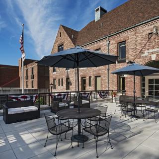 A charming patio with tables and umbrellas set against a brick building under a clear blue sky.