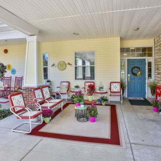 A cozy patio area with red and white furniture, potted plants, and decorative accents.