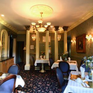 An elegantly decorated dining room with classical elements and a chandelier.